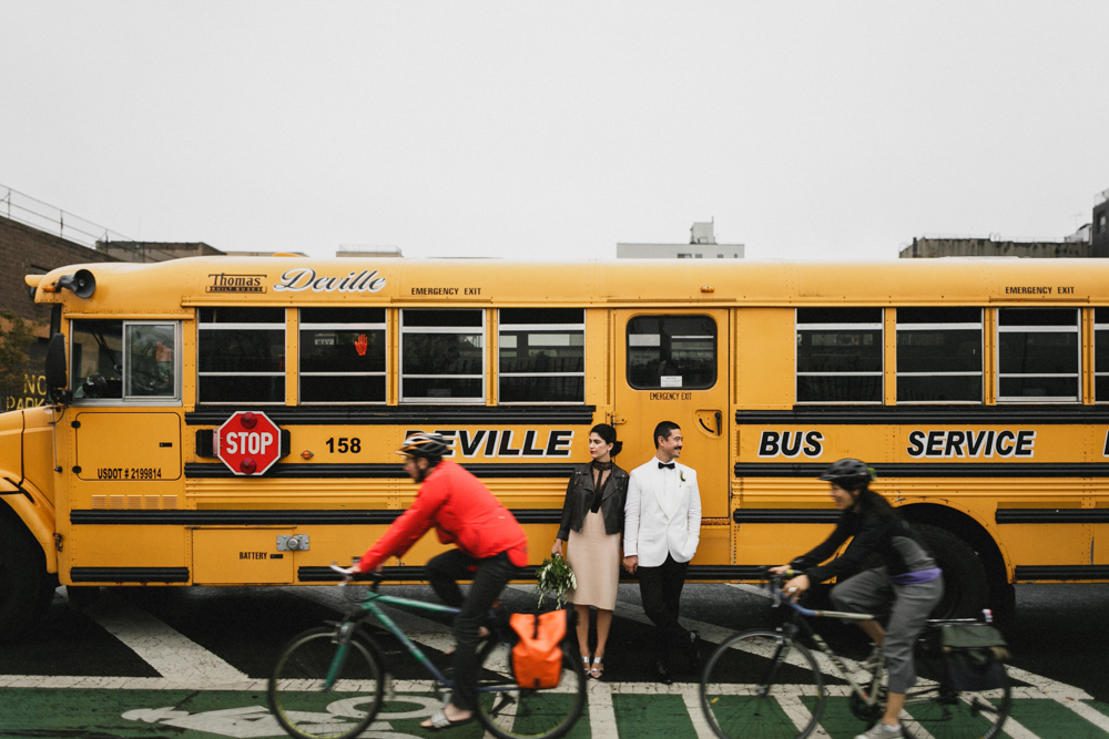Bride and groom standing in front of a yellow school bus in Brooklyn NY