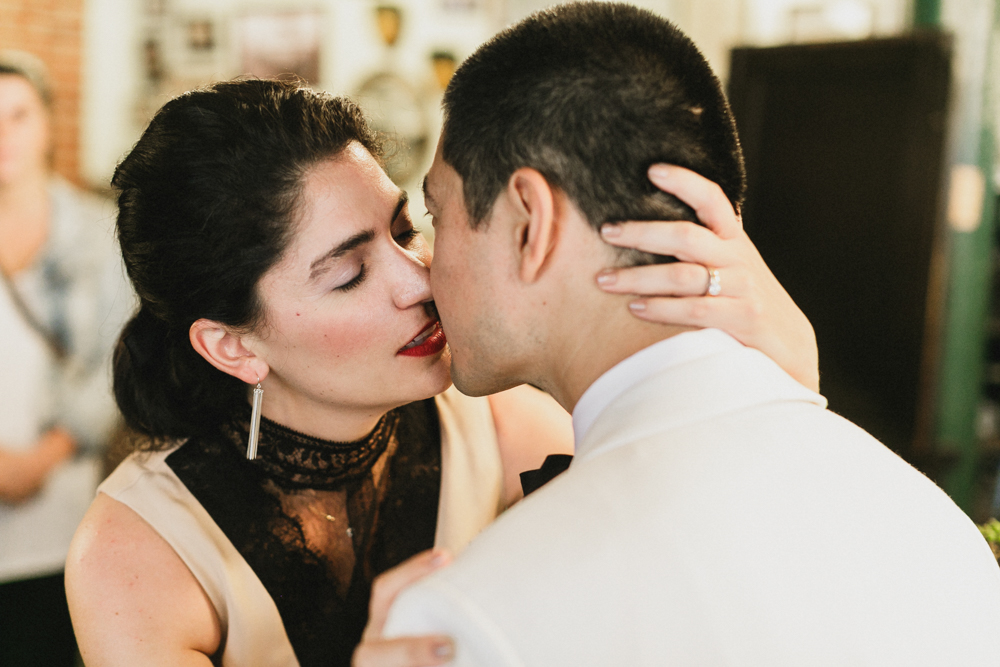 Bride and groom sharing a kiss at a bar on their wedding day. Brooklyn NY