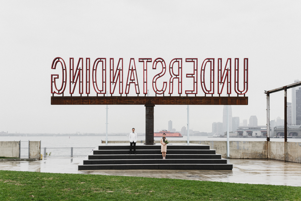 Bride and groom on their rainy day wedding standing at a pier in Brooklyn NY