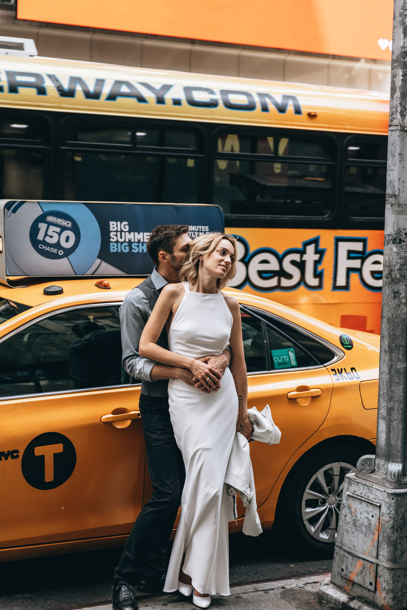 Bride and groom standing next to a yellow cab in Manhattan on their elopement day.