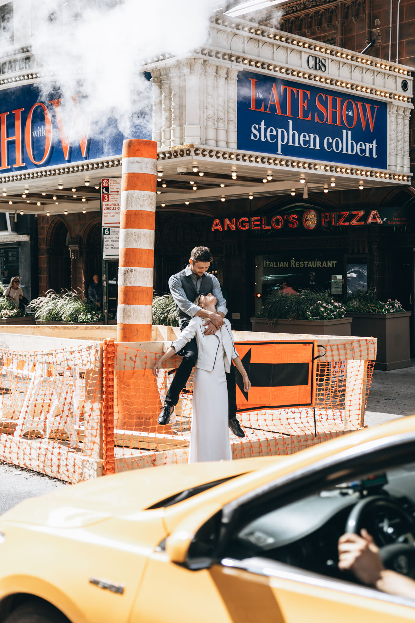 Bride and groom standing next to a yellow cab in Manhattan on their elopement day.