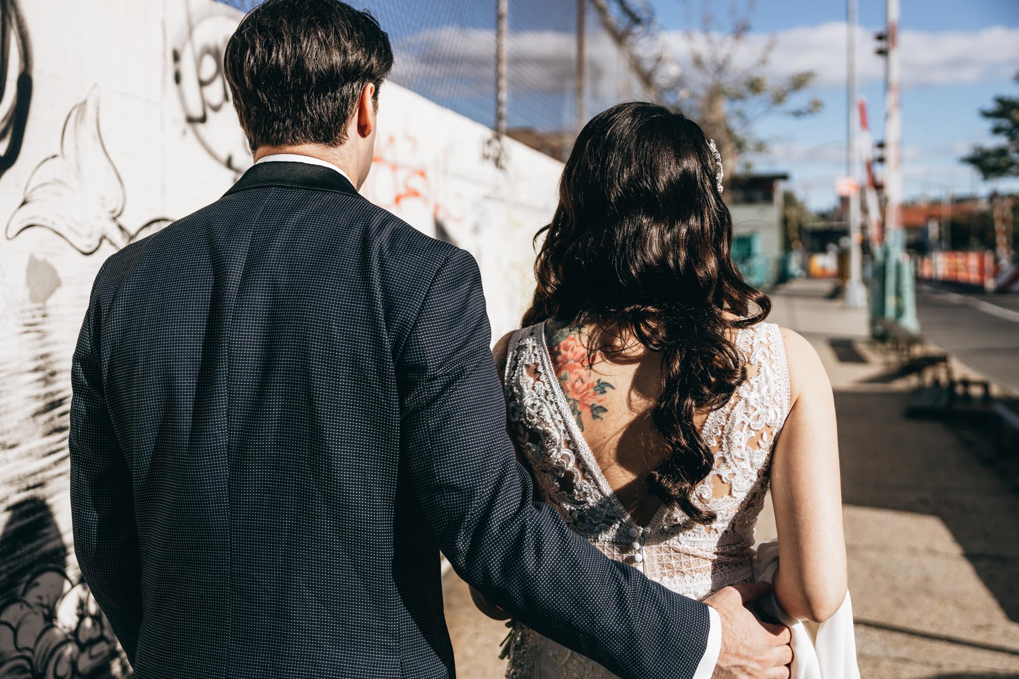 Bride with stunning tattoos walking with the groom in Brooklyn NY