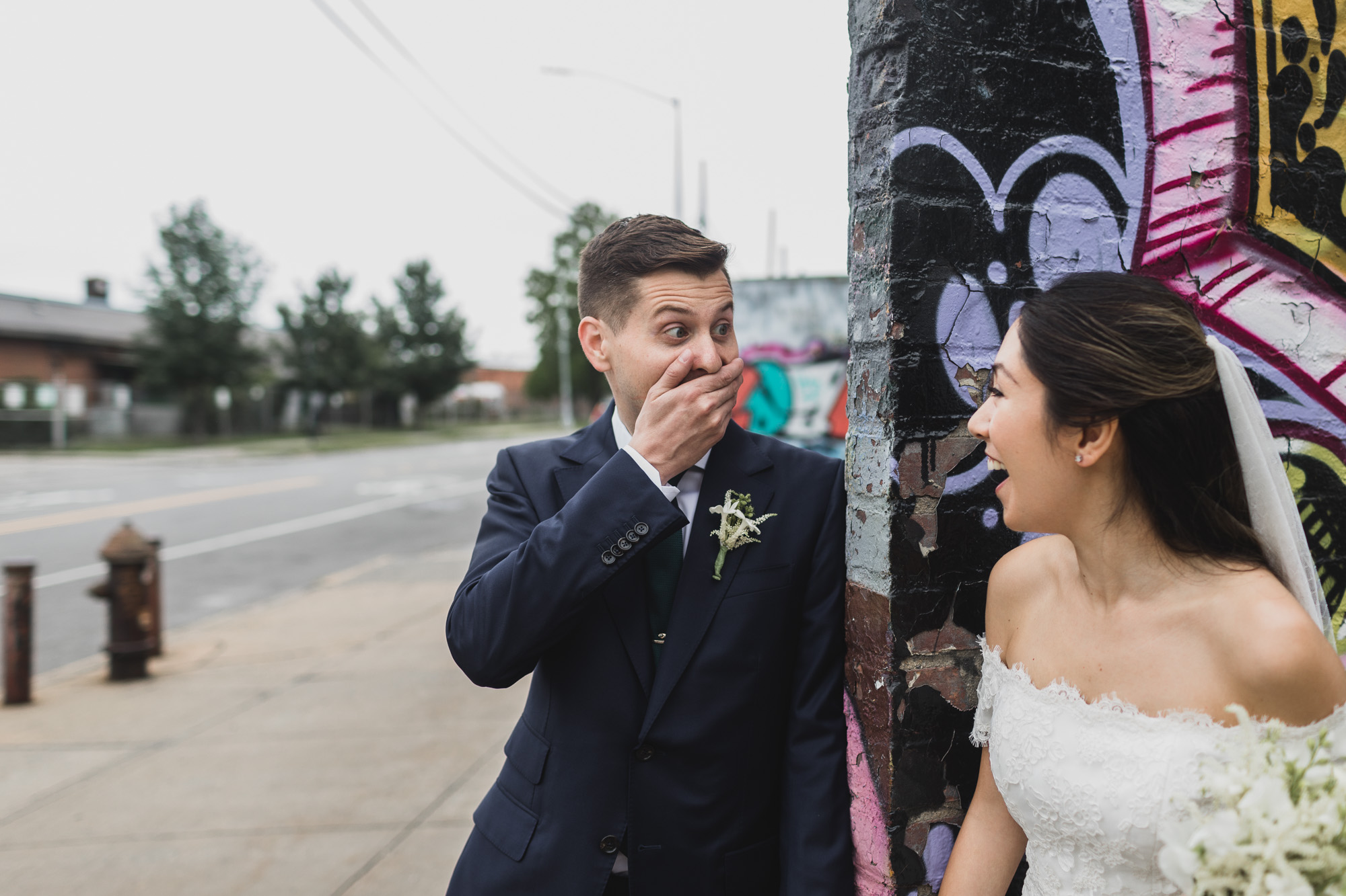 Bride and groom strolling the streets of brooklyn, amazing mural on the background.  Wedding in Williamsburg, Brooklyn