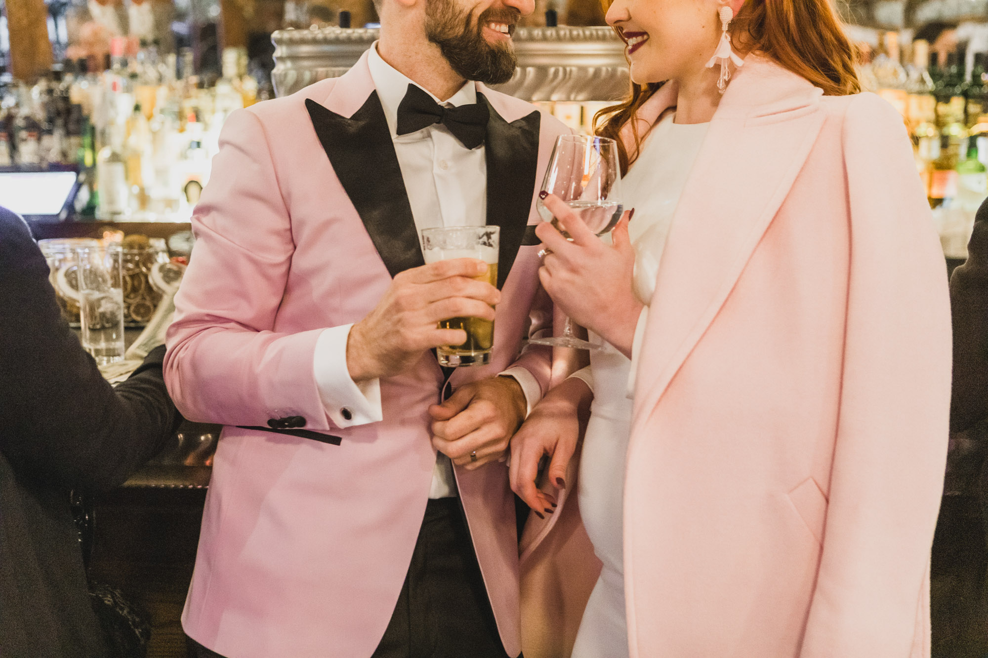 Aussie couple in light pink outfits celebrating with drinks. West Village, Manhattan NY
