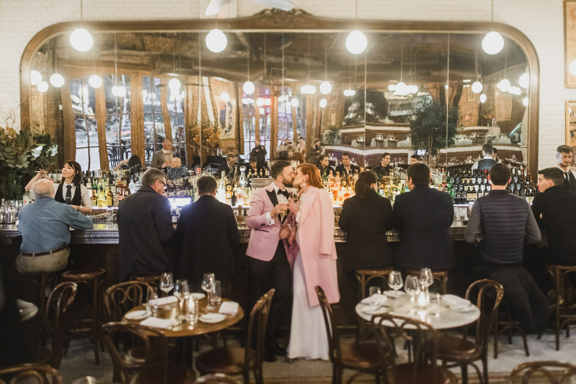 Aussie couple in light pink outfits celebrating with drinks. Bouchierie, West Village, Manhattan NY