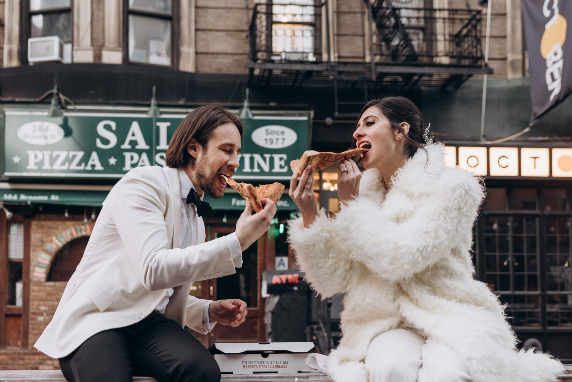 Happy bride and groom eating pizza in Little Italy during their winter elopement.  Manhattan NY 