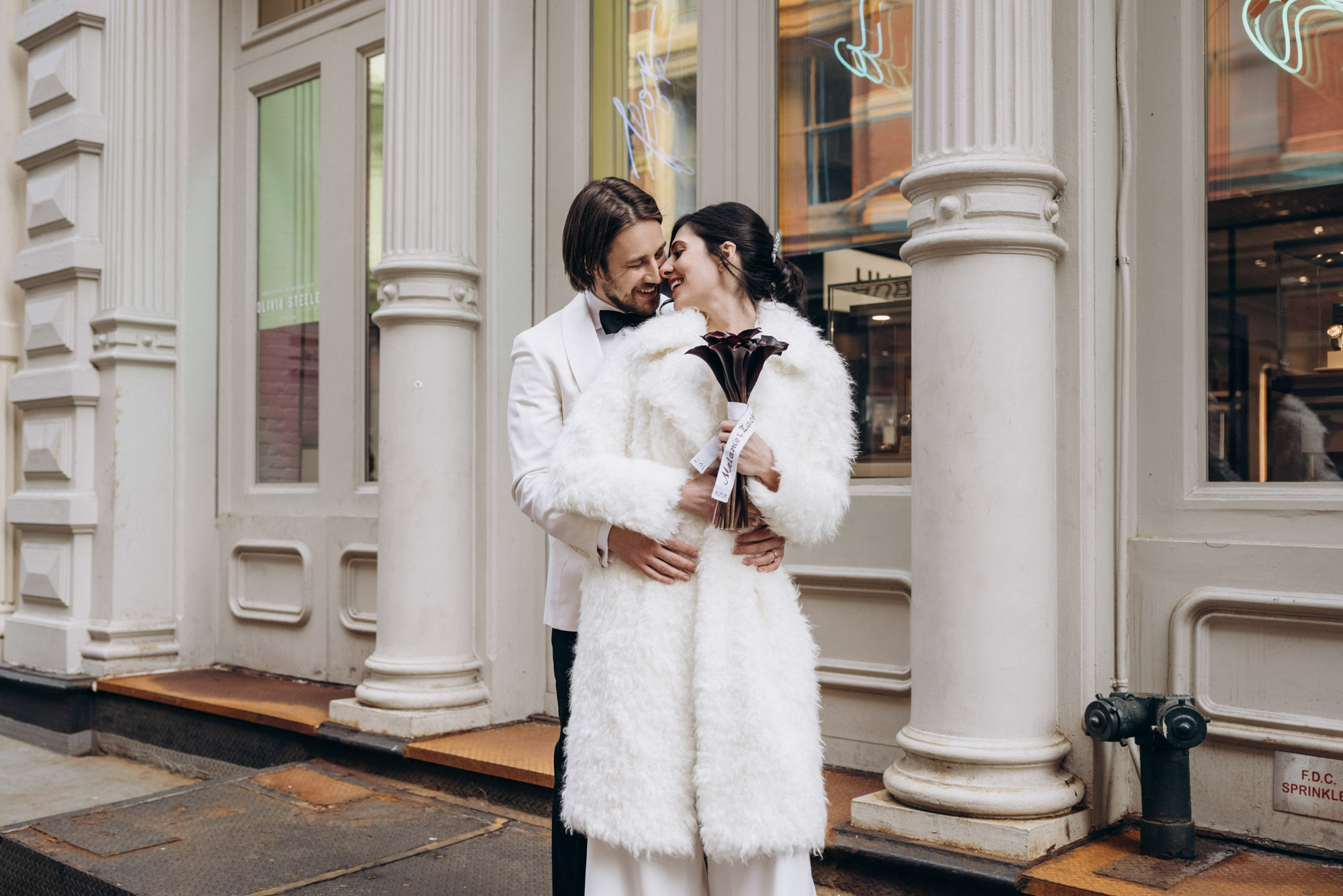 Bride and groom in a coat during their NYC winter elopement. Soho. Manhattan NY