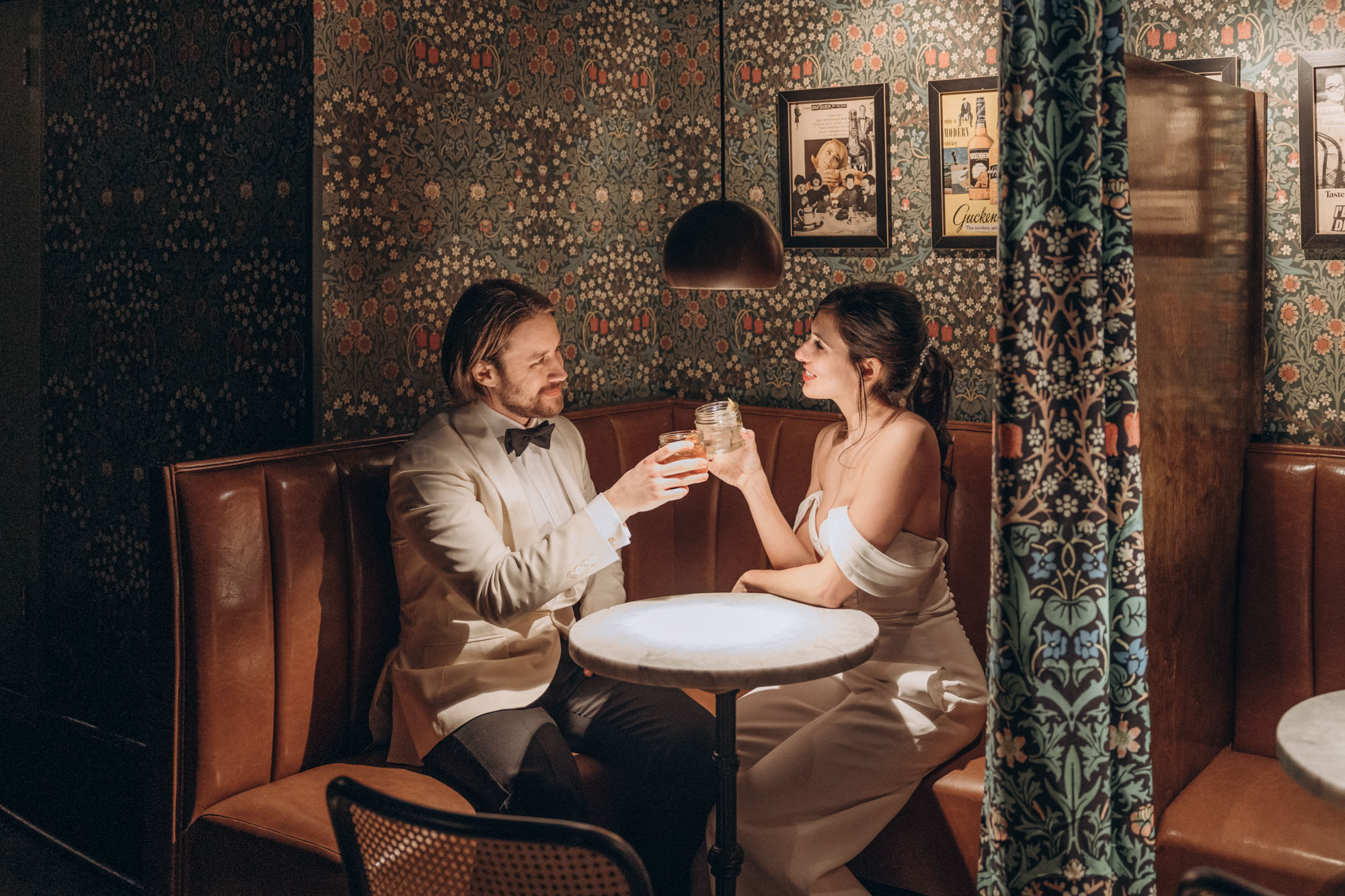 Happy bride and groom getting cocktails during their winter elopement at a cozy bar. Manhattan NY