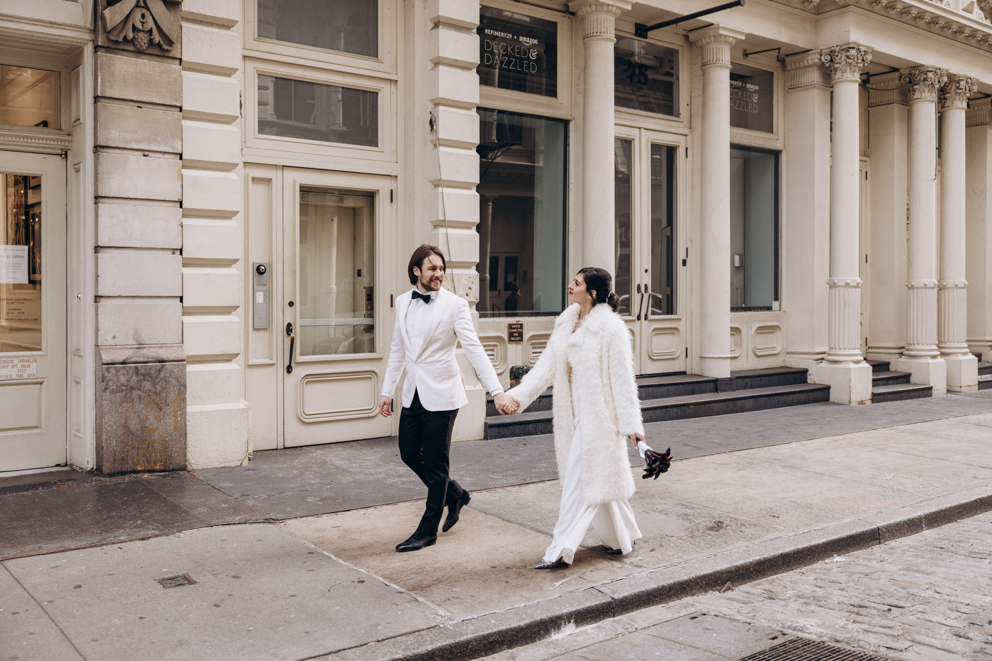 Stylish bride and groom walking on a street in Soho. Winter elopement White Soho architecture. Manhattan NY
