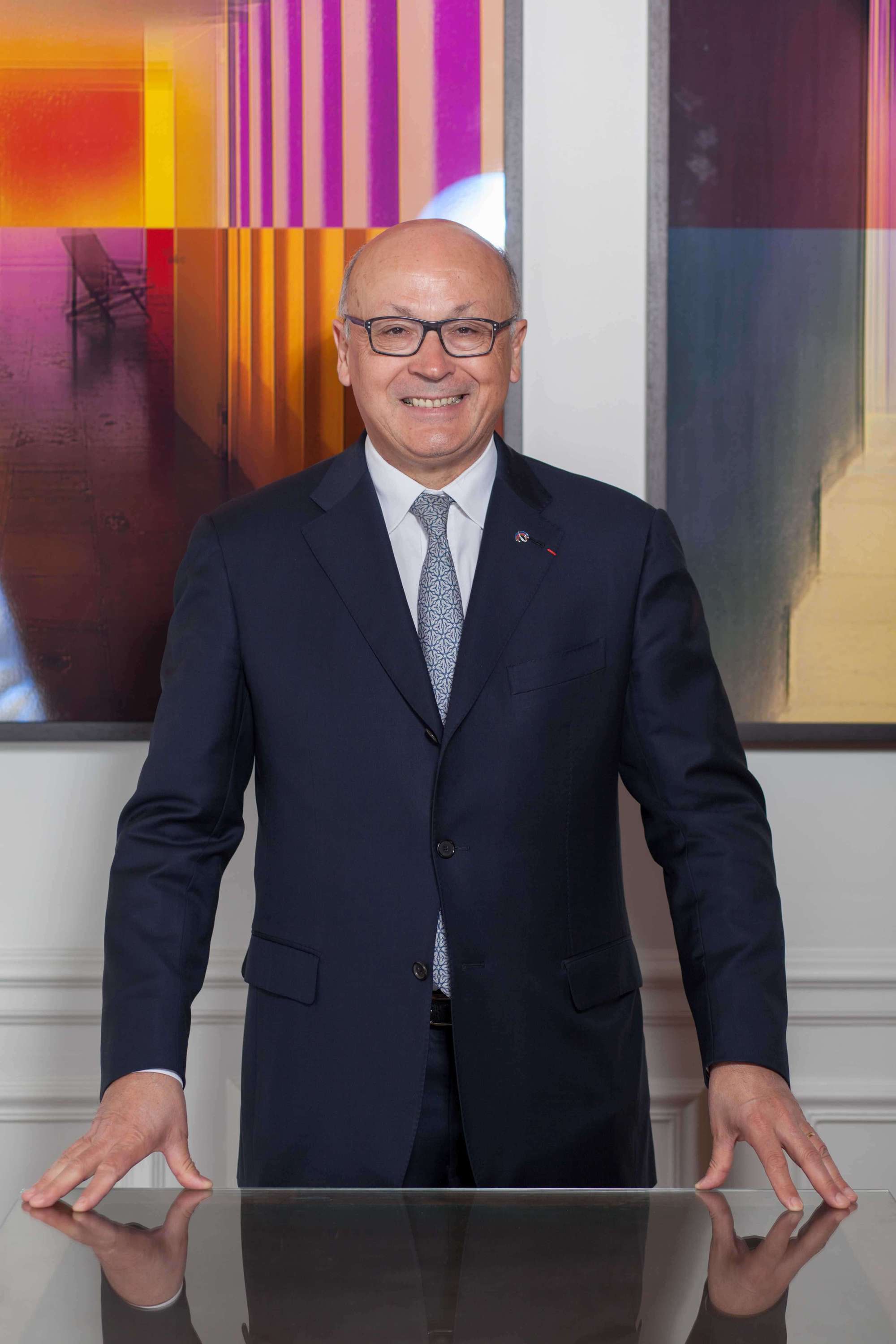 Portrait of a top manager standing with his hands on the desk on a colorful background - Best portrait photographer Paris - PhilArty