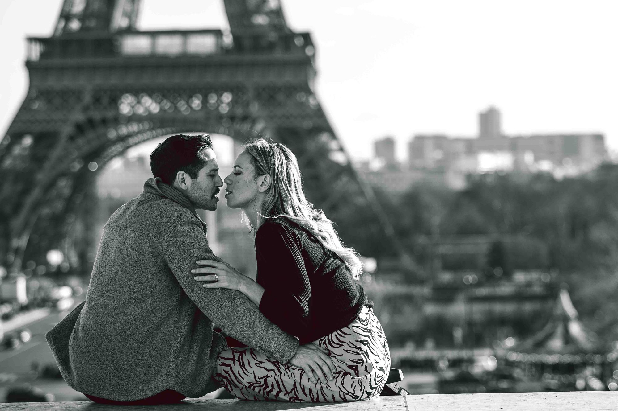 Hot couple kissing in front of the Eiffel tower in Paris. Black and white photo by PhilArty