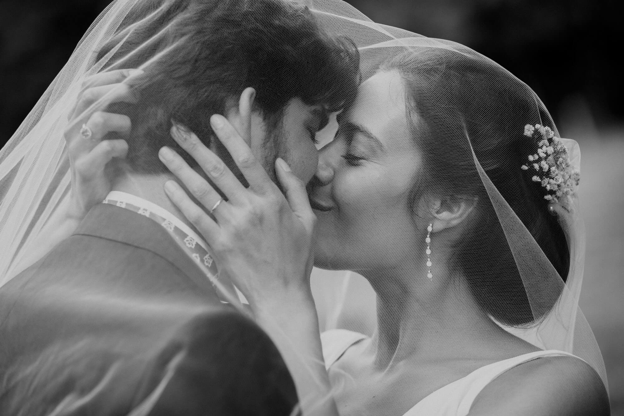Wedding photo session - Just married couple kissing under the veil shot by philarty